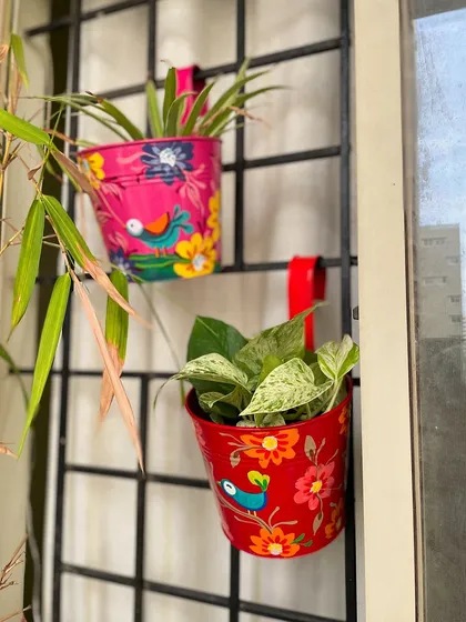 A pair of our hand-painted railing planters, adding a splash of color to a balcony window.