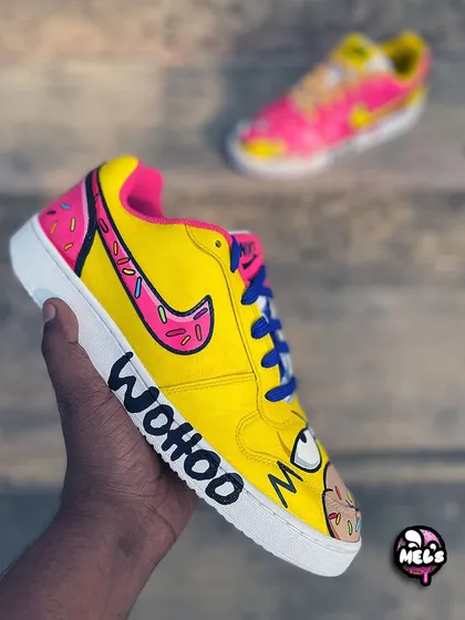 The side view of the Homer Simpson shoe, featuring his face and the "WOOHOO" text. The donut-themed swoosh ties the pair together perfectly.