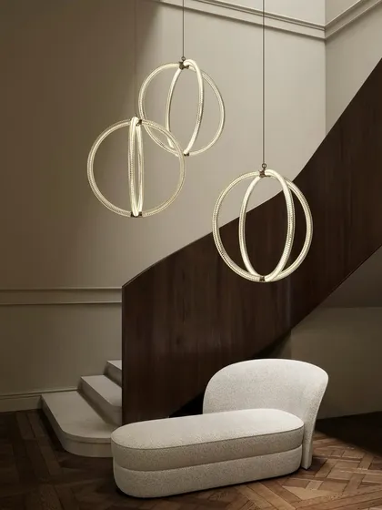 A trio of Luminora pendants cascades down a modern staircase. The torsion effect and V-shaped diamond patterns on the glass evoke the grandeur of classic ornamentation.