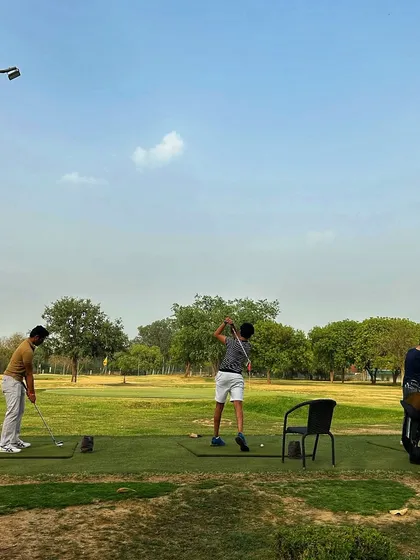 Three golfers practice on the open grass tees, enjoying the space and the clear weather.
