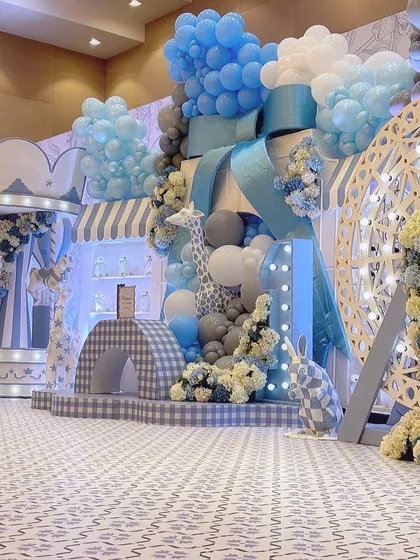 A wide shot of the carnival setup, showing the grand scale of the decor. A large blue bow and cascading balloons create a stunning photo backdrop.