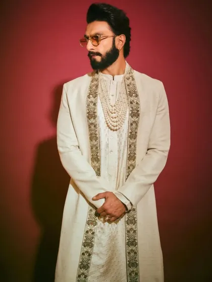 A detailed shot of the layered ivory sherwani, focusing on the textures and accessories that complete the look.