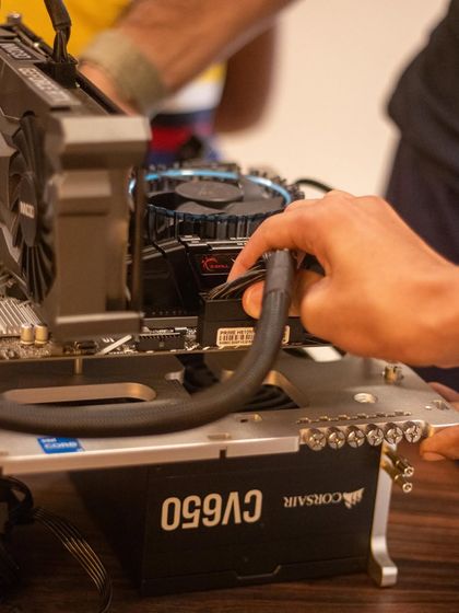 A close-up of a child connecting the power supply cables to the motherboard. This is a crucial step, and it teaches them about power distribution and cable management in a computer.