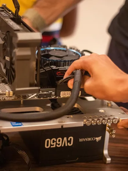 A close-up of a child connecting the power supply cables to the motherboard. This is a crucial step, and it teaches them about power distribution and cable management in a computer.