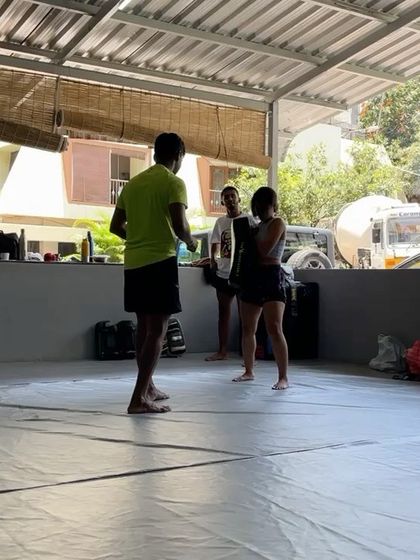 A coach providing instruction during a kickboxing drill.