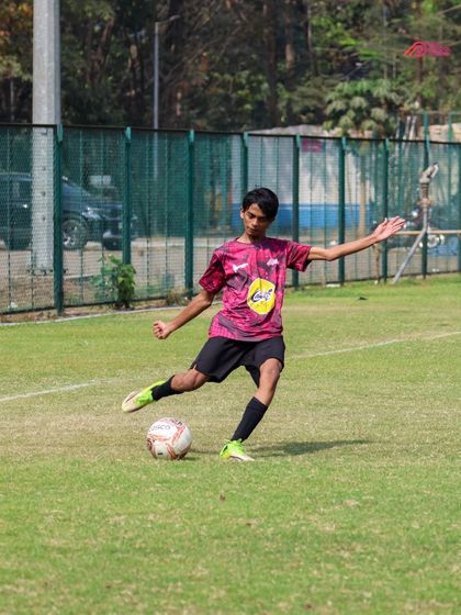 A young player lines up a pass during a competitive match, showcasing their developing tactical awareness.