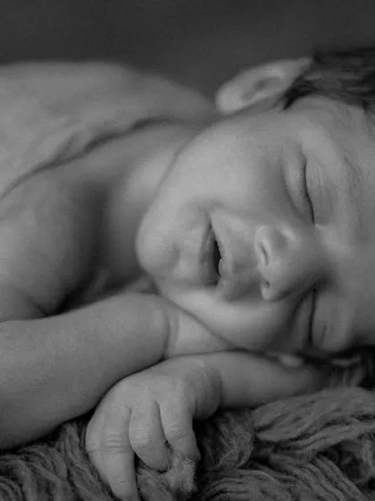 Sometimes, the smallest details tell the biggest story. This black and white close-up of a newborn's sleepy smile is a perfect example of my focus on capturing those fleeting, precious expressions that you'll cherish forever.