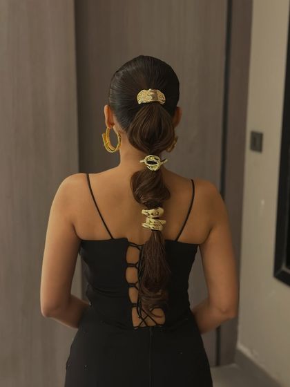 A modern and edgy bubble ponytail with chunky gold accessories. This look is perfect for a cocktail party or a fashion-forward event.