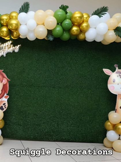A clean and modern jungle theme photo booth with a grass wall, animal cutouts, and a simple balloon garland.