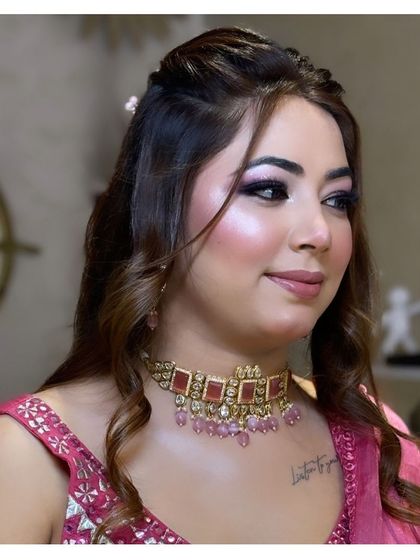 This client is ready for her event with a beautiful pink-toned makeup look and soft curls, highlighting her features perfectly.