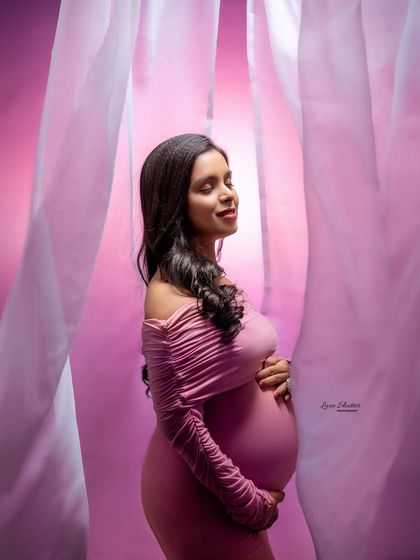 This profile shot beautifully showcases the baby bump against a soft pink backdrop. The gentle light and serene expression make this a truly peaceful and loving portrait.