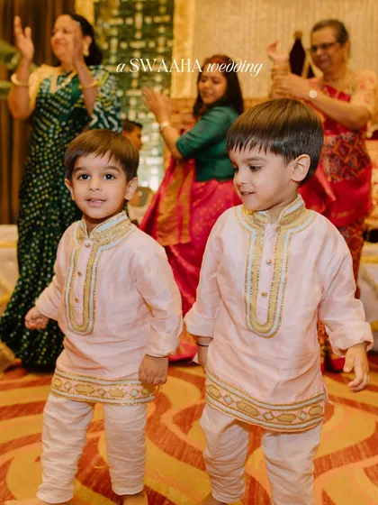 The youngest guests, two adorable boys in matching pink kurtas, enjoying the celebration.