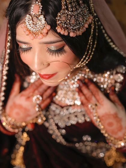 A beautiful high-angle shot of a Muslim bride, focusing on her elegant pose and the stunning details of her bridal look.