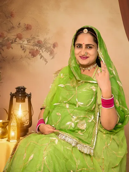 A classic solo portrait of a mom-to-be in a vibrant green traditional Rajasthani outfit. The warm light from the lantern prop adds a vintage and authentic feel to this beautiful cultural shot.
