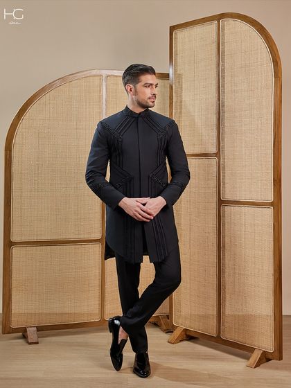 This embroidered achkan makes a definitive statement. The geometric embroidery and pleated fabric panels create a look that is both regal and fashion-forward.