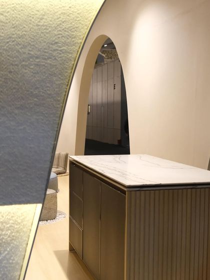 Another detail of the Plüsch booth, showing the fluted texture of the island counter and the soft, arched corridor in the background. The design is a narrative of texture, light, and form.