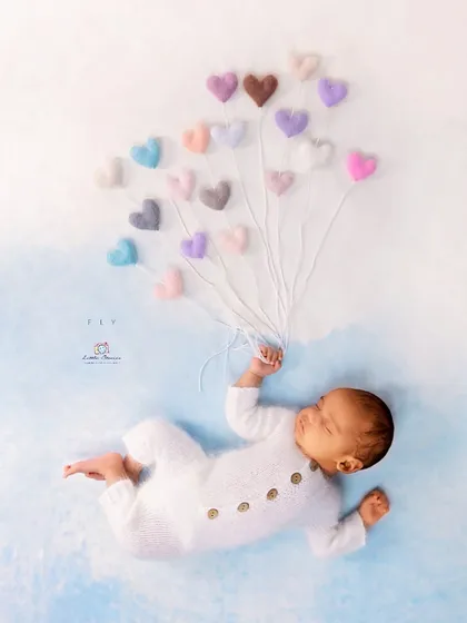 This is an example of a whimsical and creative setup. I used soft, felted hearts as balloons to create a sweet, imaginative story, showing how props can add a touch of playful magic to a newborn photo.