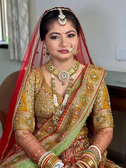 A full portrait of the bride, showcasing the complete look. The makeup harmonizes with the gold and green tones of her lehenga for a classic and cohesive feel.