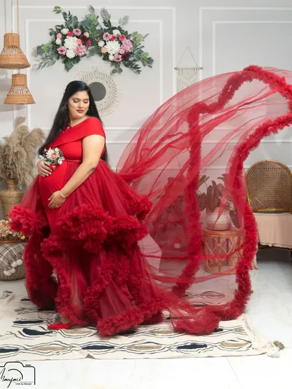 A dramatic fabric toss with a bold red gown in the boho setup. The contrast between the vibrant red and the neutral background is striking.