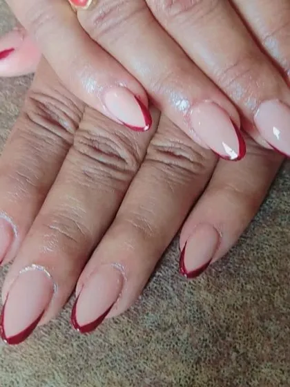 An elegant and sophisticated French manicure using a deep maroon for the tips on almond-shaped nails. The sharp V-shape gives it a very modern and chic feel.