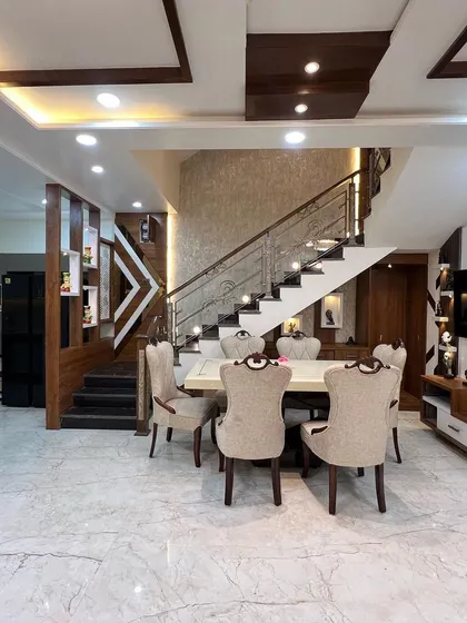 From this perspective, you can see how the dining area is nestled under the staircase. This efficient use of space is complemented by the multi-level false ceiling and textured accent wall.