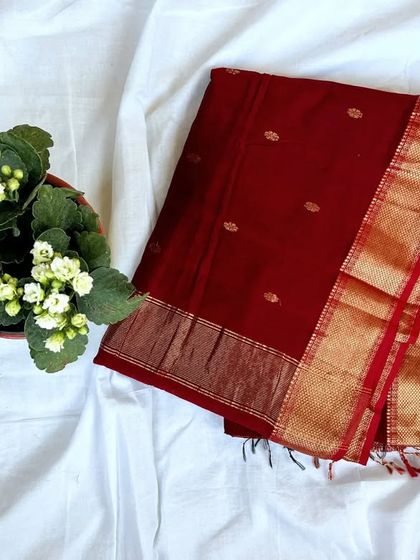 A deep maroon Maheshwari silk cotton saree with delicate gold butti work and a rich zari border.