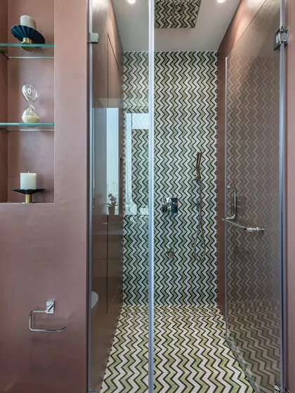 This shower area features a playful chevron pattern tile in shades of green. The design adds a pop of color and personality to the bathroom, complemented by the dusty rose color on the walls.