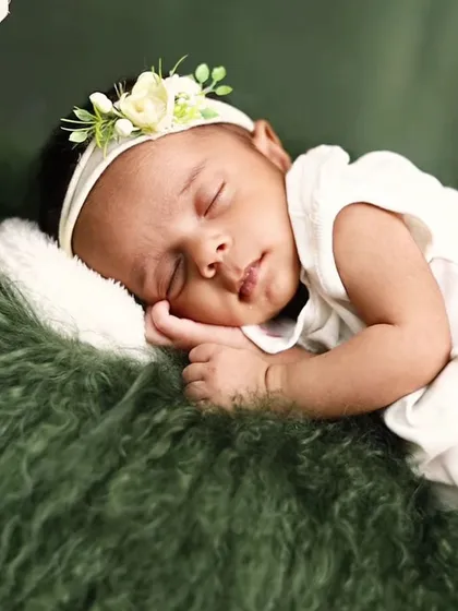 A close-up of a sleeping newborn resting on a soft, green fur blanket. We focus on capturing the peaceful expressions and tiny details, like their hands and lips.
