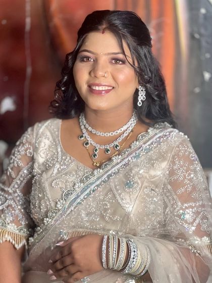 This client is styled for a party in a light-colored lehenga. Her hair is in a simple half-updo with curls, a look that is both elegant and easy to manage.