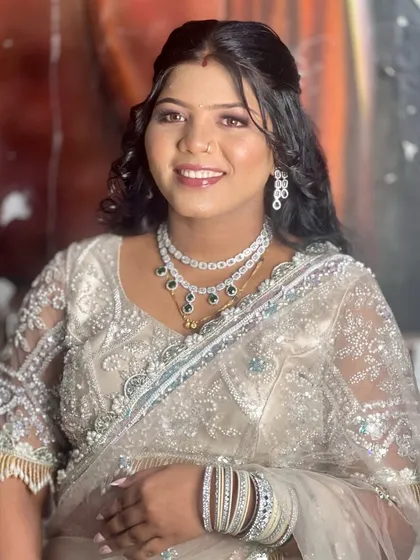 This client is styled for a party in a light-colored lehenga. Her hair is in a simple half-updo with curls, a look that is both elegant and easy to manage.