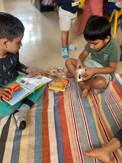 Two boys sit on the floor, sharing a book and discussing the pictures. This is where friendships are built over a shared love for stories.