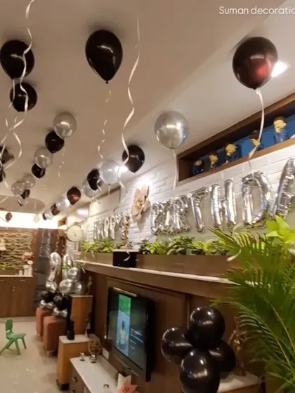 A view of the room decoration from another angle, showing the "Happy Birthday" foil balloon banner above the main seating area.