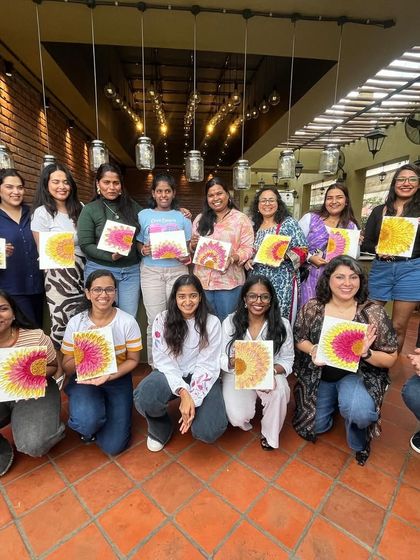 The whole group from a texture painting workshop, kneeling with their finished sunflower artworks.