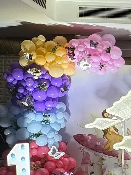 Colorful balloon clusters with butterfly accents, part of the decor for the enchanted garden theme.