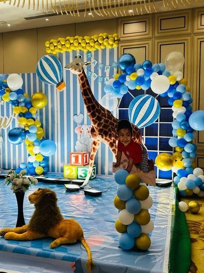 A safari adventure theme with a large giraffe prop, a lion, and hot air balloon cutouts against a blue and white striped backdrop.