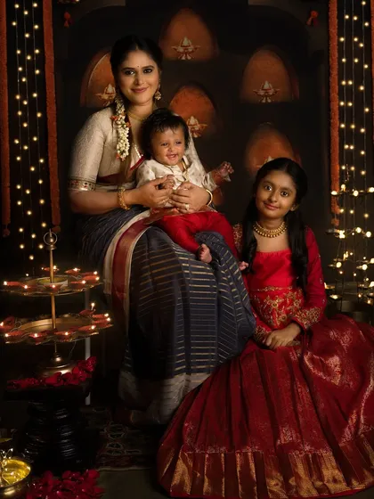A mother and her two children, dressed in festive red, pose for a beautiful Diwali family portrait.