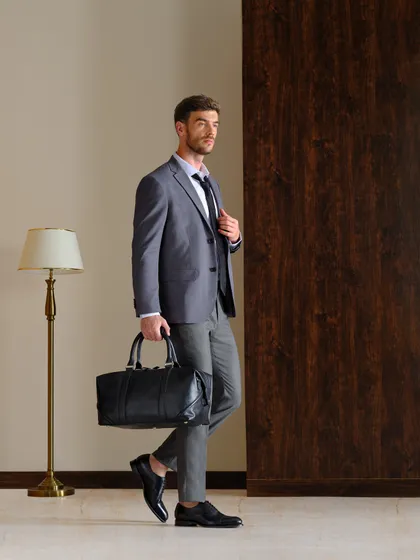 A polished and professional look for a men's formalwear and accessories campaign. The styling of the grey suit and black leather bag is aimed at the modern working man.