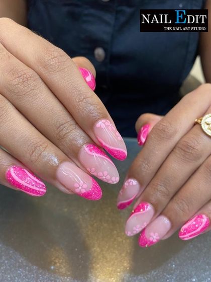A bright and cheerful pink manicure. This design combines sparkling pink glitter nails with accent nails featuring a sheer base and delicate pink floral patterns.