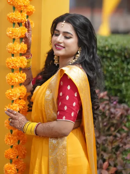 The bride posing next to marigold flower decorations, perfectly matching the Haldi theme.