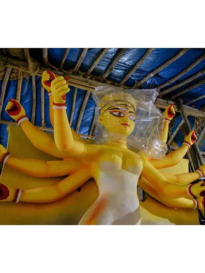 An unfinished idol of Goddess Durga, her eyes yet to be painted, wrapped in plastic for protection. This marks the beginning of the final preparations for Durga Puja.