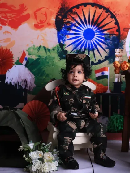 Posing with pride, this little one in an army uniform holds a prop for his Independence Day portrait. The colorful backdrop with the Ashoka Chakra and Indian flag colors completes this patriotic theme.