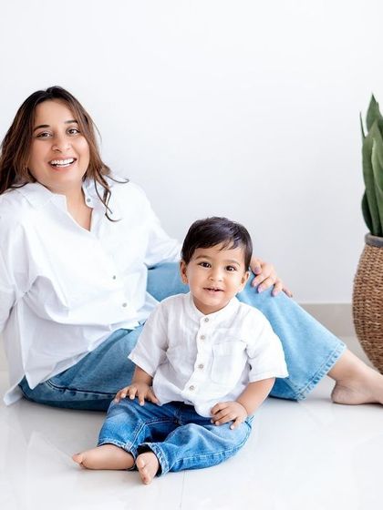 A relaxed family portrait in the studio, with mom, dad, and their little one dressed in casual jeans and white shirts.