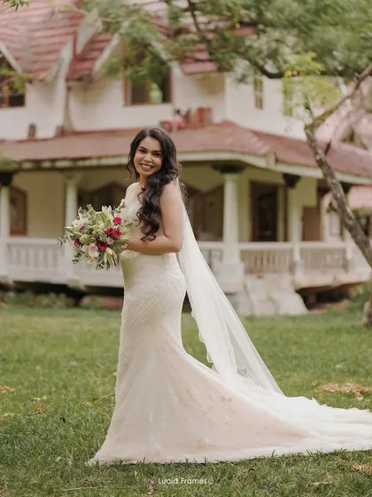 A stunning portrait of the bride in her beautiful gown and long veil, with a charming house in the background.