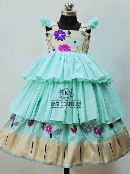A modern tiered frock in a lovely pastel blue. The yoke features floral embroidery, and the skirt has a traditional Kanchi border.