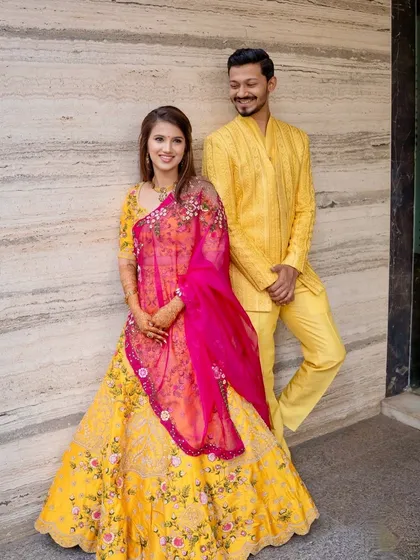 A full-length portrait of the couple. The bride's vibrant lehenga and soft makeup create a beautiful contrast.