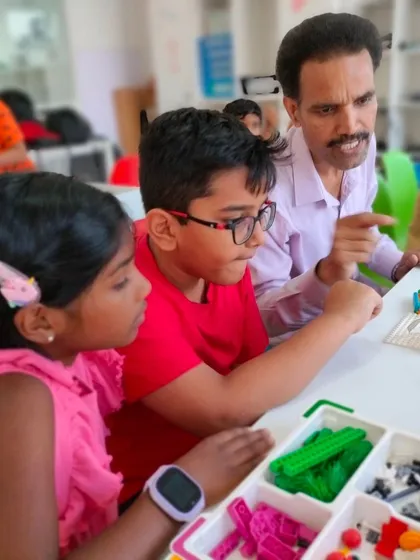 Our instructors are experts at making learning fun. Here, an instructor points out a key step to two students as they assemble their LEGO project, ensuring they understand the mechanics.