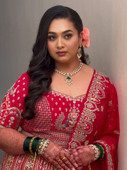 A bold and beautiful reception look. The client is wearing a vibrant red lehenga, and we paired it with smoky eyes and loose waves for a touch of glamour.