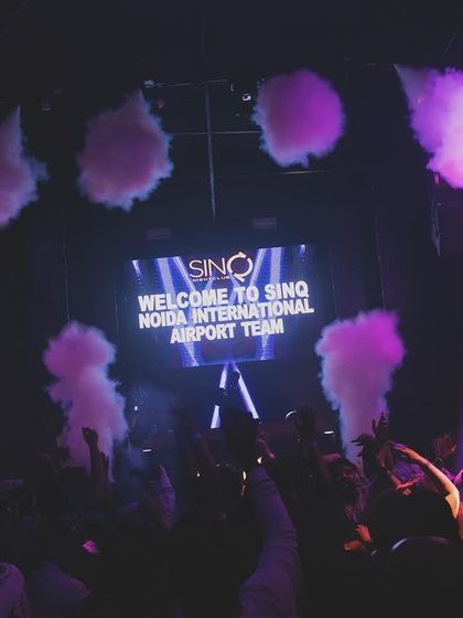 Plumes of purple smoke rise towards the ceiling at SinQ, creating a cool, atmospheric effect during a corporate event for the Noida International Airport team.