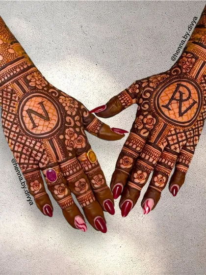 This personalized back-hand design showcases the initials 'N' and 'RV' in the center of intricate mandalas. The rich color and detailed work make it a standout piece.