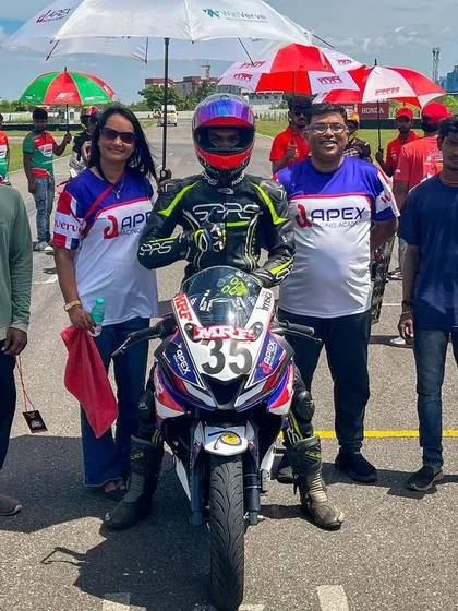 A rider stands proudly with his team and family on the starting grid. This image shows the crucial support network that stands behind every racer on their journey.